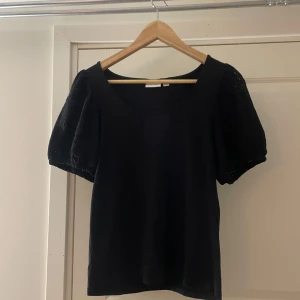 Svart topp med puffärmar - En svart topp med korta puffärmar och rund halsringning. Den är liten i storleken så jag skulle säga att den sitter som storlek S. 
