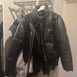 Svart pufferjacka från Chiquelle - Svart pufferjacka i syntetmaterial. Jackan har en dragkedja framtill och är perfekt för kyliga dagar. Den är i bra skick och har en modern, croppad stil. Passar perfekt för höst och vinter! Nypris 900kr, mitt pris 200kr då det är ett hål inuti jackan går att använda den utan problem annars lättlagat:)