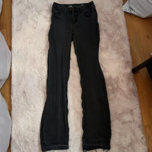 Svarta mid bootcut jeans - Säljer ett par svarta/mörkgrå jeansbyxor i bra skick. De har en klassisk bootcut-stil och är perfekta för både vardag och fest. Byxorna har en normal passform (mid/low waist) och är tillverkade i ett bekvämt jeansmaterial. Perfekta för höst och vinter!
