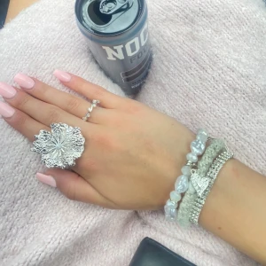 Blommig ring - Säljer en stor, glittrig silverfärgad ring med ett unikt blommönster. 