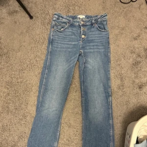 Blå jeans från Gina Tricot - Säljer ett par snygga blå jeans från Gina Tricot i storlek 164. De har en snygg framsida med 3 knappar och är lågmidjade. Perfekta för vardagsbruk och kan matchas med nästan vad som helst. Passar både till sneakers och klackar! Kontakta för mer💗