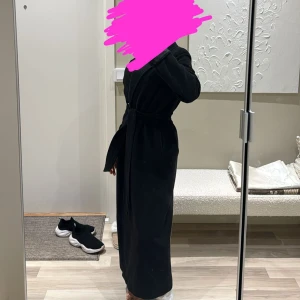 Lång Svart kappa med bälte - oanvänd - Säljer min svarta kappa som är helt oanvänd, säljer den pga storlek då jag vill ha en lite mer oversize modell. Bältet medförljer. Passar jättebra under vintern då den är tålig mot kylan. Köpt för 999kr säljer för endast 599kr. Priset går att diskutera vid snabb affär.