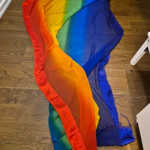 Sarong/sjal - Sarong/strandplagg/sjal i vackra färger. Tyget är lätt genomskinligt, se bilder. Fransar på kortsidorna och mönster på långsidorna. Köpt i Grekland.