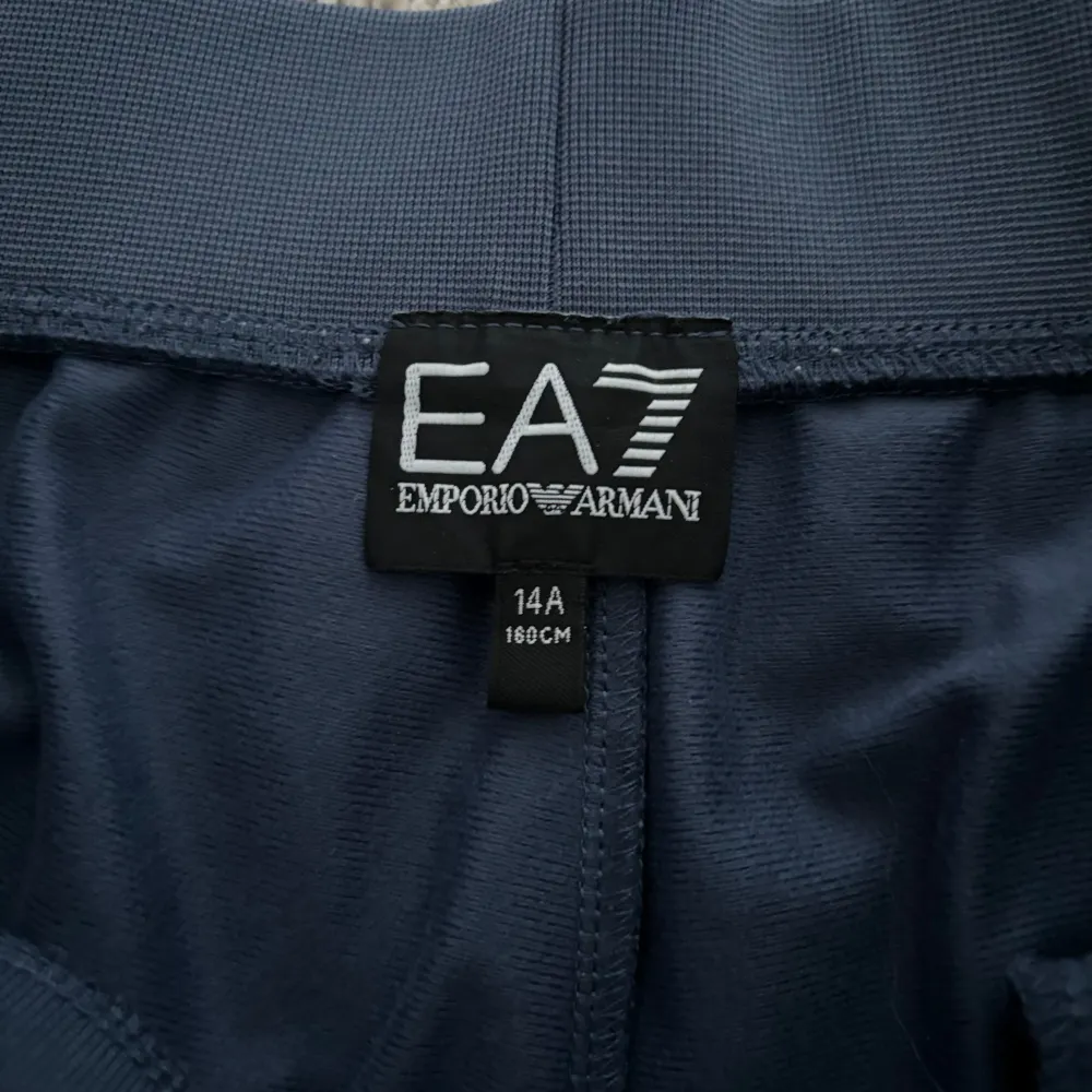 Säljer ett par snygga mörkblå mjukisbyxor från Emporio Armani. De har en stilren design med EA7-loggan tryckt på sidan. Byxorna är gjorda i ett mjukt och bekvämt material, perfekt för både träning och chill. . Jeans & Byxor.