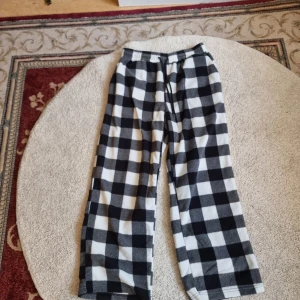 Svartvita rutiga byxor från Manfinity - Säljer ett par superbekväma svartvita rutiga byxor från Manfinity. De är i storlek M och har en elastisk midja med snörning för extra komfort. Perfekta för en avslappnad dag hemma eller som mysbyxor. Materialet känns mjukt och skönt mot huden. Baggy