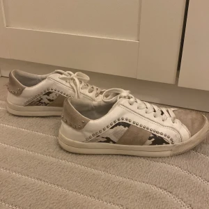 Skor Zara - Snygga vita sneakers med coola nitar och kamouflagemönster i beige och svart. Skorna har snörning. Inga defekter behöver bara rengöras 