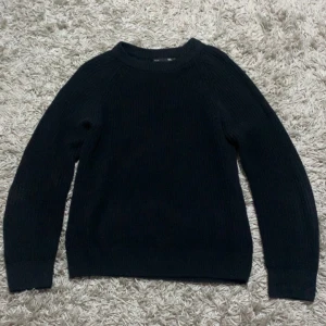 Svart stickad tröja från 157 - Säljer en stilren svart stickad tröja från 157. Tröjan har en klassisk design med rund hals och långa ärmar, perfekt för kyligare dagar. Passar bra till både jeans och chinos. Ett måste i garderoben för en enkel och snygg look.