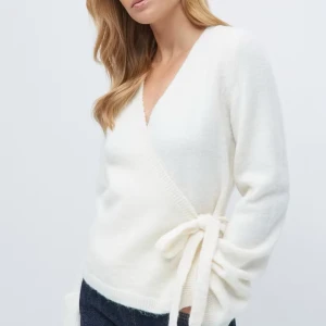 Vit omlottkofta med knytband - Säljer en stilren vit omlottkofta med knytband i sidan. Koftan har en v-ringad design och långa ärmar, perfekt för en elegant och bekväm look. Passar utmärkt till både jeans och kjol.