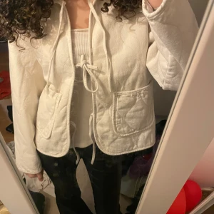 Vit quiltad jacka från Vero Moda - Säljer en snygg vit quiltad jacka från Vero Moda. Jackan har långa ärmar och praktiska fickor framtill. Den har en knytning i midjan för en justerbar passform. Perfekt för en stilren look!