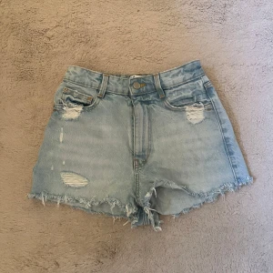 Ljusa jeansshorts med fransar - Högmidjade korta jeansshorts med slitna detaljer.  Fickor både framtill och baktill. Använda fåtal gånger men de har inga defekter. 