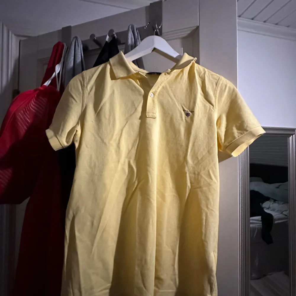 Snygg gul pikétröja från GANT med klassisk krage och knappdetalj framtill. Perfekt för en avslappnad men stilren look. Passar bra till både jeans och chinos. Storlek 164 cm vilket motsvarar xs. Obs! Tröjan strycks innan den skickas👍. T-paidat.