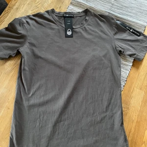 Brun t-shirt från Sail Racing - Snygg brun t-shirt från Sail Racing i storlek XS. Tillverkad i mjukt material med rund hals och korta ärmar. Perfekt för en avslappnad stil.