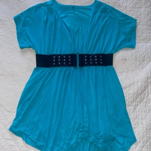 Blå klänning med bälte - Snygg blå klänning med korta ärmar och ett brett svart bälte med nitar. Perfekt för en cool och avslappnad stil. Klänningen har en lös passform och är tillverkad i ett lätt material.