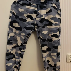 Kamouflagefärgade mjukisbyxor för barn - Säljer ett par bekväma kamouflagefärgade mjukisbyxor för barn. Byxorna har ett elastiskt midjeband och är perfekta för en avslappnad stil. Tillverkade i Turkiet.