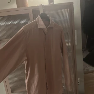 Rosa skjorta från Eton - Säljer en stilren gammal rosa skjorta från Eton i storlek M. Skjortan har långa ärmar och knappar framtill. Perfekt för en elegant look.