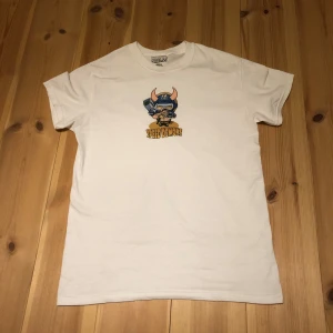 Vit t-shirt från Speed Demons - Säljer en helt ny vit t-shirt från Speed Demons med ett coolt tryck av en tecknad figur med horn och texten 'Speed Demons' i gult. Perfekt för dig som gillar unika och roliga motiv! Det finns även stickers om man vill ha det.