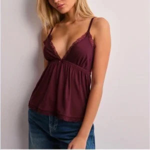 Vinröd linnetopp med spetsdetaljer - Snygg vinröd linnetopp med smala axelband och spetsdetaljer vid urringningen. Perfekt för en stilren och bekväm look.
