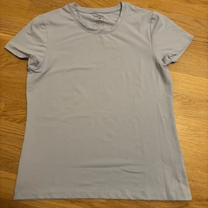 Ljusblå t-shirt från Energetics - Säljer en ljusblå t-shirt från Energetics. Den har en enkel design med rund hals och korta ärmar. Perfekt för en avslappnad stil eller träning. Materialet känns mjukt och bekvämt mot huden.