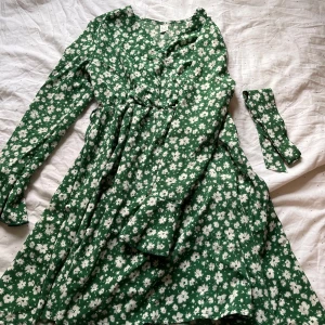 Grön blommig klänning från Shein - Söt grön klänning med vita blommor från Shein. Klänningen har långa ärmar och ett knytband i midjan för en fin passform. Perfekt för vår och sommar! Använd 2 gånger🫶🏼