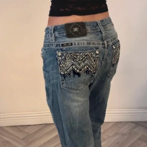 Miss me jeans - Snygga blå jeans från Miss Me med unika pärldetaljer och mönster på bakfickorna. Jeansen har en straight passform dom är baggy skit snygga med tajt långärmad tröja till! 🥰midja 42/43 ca innerbensmått 77 ca finns slitage vid fötterna men inget man tänker på🥰😍