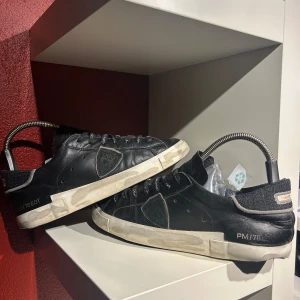 Svarta Philippe Model skor - Snygga svarta Philippe Model skor med vita sulor och fin snöring. Skorna har en stilren design med diskreta detaljer och text på snörena. Perfekta för en avslappnad stil. Hör av er vid minsta fundering 🍾