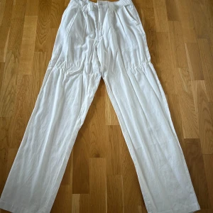 Vita linnebyxor från 157 - Snygga vita linnebyxor från 157 i storlek S. Byxorna har en avslappnad passform med hög midja och knäppning fram. Perfekta för en somrig look! Aldrig använda
