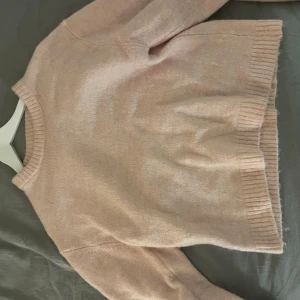 Rosa stickad tröja - Mysig rosa stickad tröja med rund hals och långa ärmar. Perfekt för kyligare dagar och ger en avslappnad look. Ribbstickade muddar vid ärmslut och nederkant. Den har endast använts två gånger.