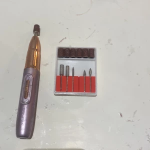 Elektrisk nagelfil med tillbehör - Säljer en elektrisk nagelfil i metallisk färg med flera utbytbara sliphuvuden. Perfekt för manikyr och pedikyr hemma. Inkluderar olika former av sliphuvuden för precisionsarbete.