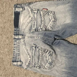 Blå jeans från Lofur's - Snygga blå jeans från Lofur's med en klassisk design. De har en rak/flare passform och knappar längs sidorna. Säljer pga att dom är för små!