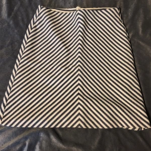 Randig kjol från Reserved - Snygg randig kjol från Reserved i svart och vit. Kjolen har ett diagonalt randigt mönster som ger en cool effekt. Perfekt för att ge din outfit en stilren touch. Omsydd så uppskattas till storlek S. 