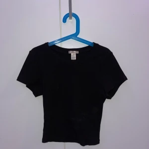 Svart ribbad topp från Bozzolo - Säljer en svart ribbad topp från Bozzolo i storlek S. Toppen har korta ärmar och en rund halsringning. 