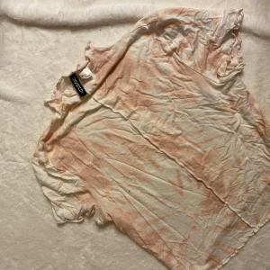 Vit och rosa t-shirt från Divided - Säljer en vit och rosa t-shirt från Divided. T-shirten har korta ärmar och ett avslappnat utseende med ett lätt mönster i rosa nyanser. Perfekt för en casual look.