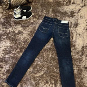 Mörkblå jeans från Replay - Snygga mörkblå jeans från Replay med klassisk femficksdesign och guldfärgade sömmar. De har en normal passform och är perfekta för en stilren look. Märkeslogga på baksidan av midjan. Ny pris 1899 knappt använda st 29/32 slim fit anbass