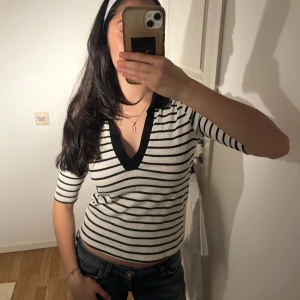 Randig ribbad topp - Supersöt vit o svart randig ribbad topp med v-ringning. Toppen har trekvartsärmar o tight passform💌