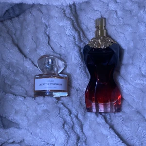 Parfymflaskor Creative Visionary och Silhuett - Två eleganta parfymflaskor. Den första är Creative Visionary, en klar glasflaska med en rundad kork och minimalistisk etikett. Den andra är en silhuettformad flaska i rött och svart med en dekorativ guldfärgad topp. Perfekt för den som vill ha en stilfull doftupplevelse.