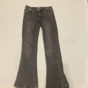 Grå bootcut jeans från Gina Tricot - Snygga grå bootcut jeans från Gina Tricot i storlek 146. Perfekta för en trendig look med sin klassiska femficksdesign och bekväma passform. Dessa jeans har en stilren grå färg och är tillverkade i ett slitstarkt material.