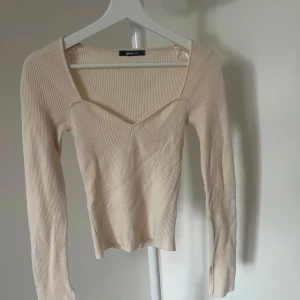 Beige ribbad tröja från Gina Tricot - Säljer en stilren beige ribbad tröja från Gina Tricot. Tröjan har en v-ringad design och långa ärmar. 