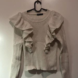 Vit ribbad tröja från Shein - Säljer en stilren vit ribbad tröja från Shein med volangdetaljer på axlarna. Tröjan har långa ärmar och en rund halsringning. Perfekt för att ge en extra touch till din outfit!