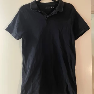 Svart kortärmad pikétröja - Snygg svart pikétröja med korta ärmar och klassisk krage. Perfekt för en avslappnad men stilren look. Passar bra till både jeans och chinos.
