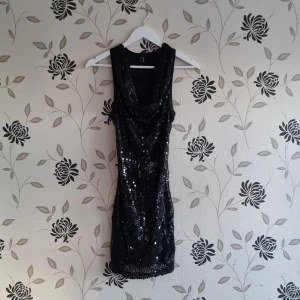 Svart paljettklänning, Vero Moda, Strl: S, nyår - Snygg svart klänning täckt med glittrande paljetter. Den har en djup v-ringning och är ärmlös, vilket ger en elegant look. Perfekt för festliga tillfällen.