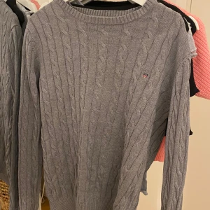 Grå finstickad tröja  - Säljer en stilren grå stickad tröja från GANT. Tröjan är köpt från Plick och är i Storlek M. En grej är att lappen är lite lös men annars är tröjan i väldigt bra skick.