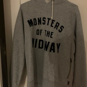 Grå NFL hoodie från Nike - Säljer en grå hoodie från Nike med texten 'Monsters of the Midway' NFL tryckt på framsidan. Tröjan har en klassisk design med långa ärmar och en dragkedja på sidan. Perfekt för en avslappnad stil.