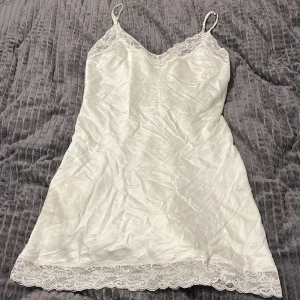 Vit klänning/linne från Intimissimi - Elegant vit klänning/linne  i siden från Intimissimi med spetsdetaljer vid halsringning och nederkant. Axelbandslös design som ger en sofistikerad look. Perfekt för speciella tillfällen.  Orginal pris 700