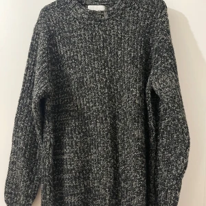 Svart och vit stickad tröja från Vailent - Mysig svart och vit stickad tröja från Vailent. Perfekt för kyliga dagar med sin tjocka och bekväma design. Tröjan har en klassisk rund hals och långa ärmar.