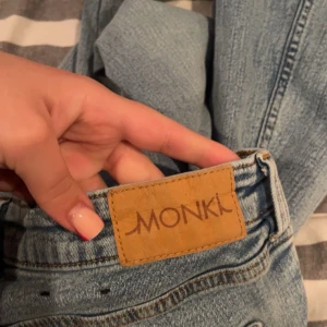 Blå jeans från Monki - Säljer ett par snygga blå jeans från Monki. De har en klassisk design med fem fickor och knappgylf. Perfekta för en avslappnad stil.