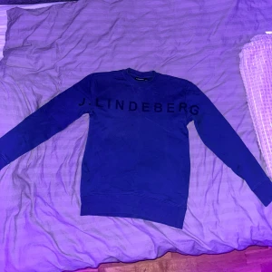 Blå tröja från J.Lindeberg - Snygg blå tröja från J.Lindeberg med långärmad design och rund hals. Perfekt för en stilren och avslappnad look. Strlk xs men passar M och S, knappt använd.