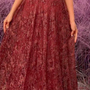 Vinröd långklänning med glittrigt mönster - Elegant vinröd långklänning med ett glittrigt mönster som ger en lyxig känsla. Perfekt för speciella tillfällen med sin vackra design och långa längd.