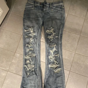 lågmidjade bootcut slitna jeans  - Såå snygga trendiga jeans. Perfekt lågmidjade och utsvängda. Med så coola slitningar!! De är från ett okänt vintage märke! Lite slitna nere vid ena benet men inget man lägger märke till.  Midja 37-38  Benöppning 23-22  Längd 104  
