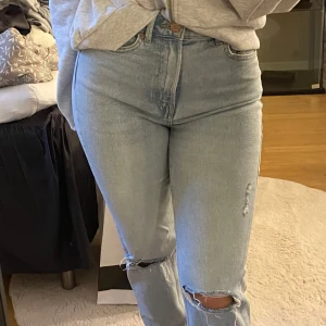 Blå raka jeans  - Blå raka jeans med hål på knäna från Stradivarius. Modellen ” mom slim” storlek 34. Bra skick. Jag är 160cm och jeansen slutar vid mina anklar. 
