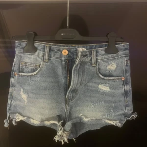 Jeansshorts  - Ett par jeans shorts med slitna märken Det står storlek 36 men det känns mer som 34